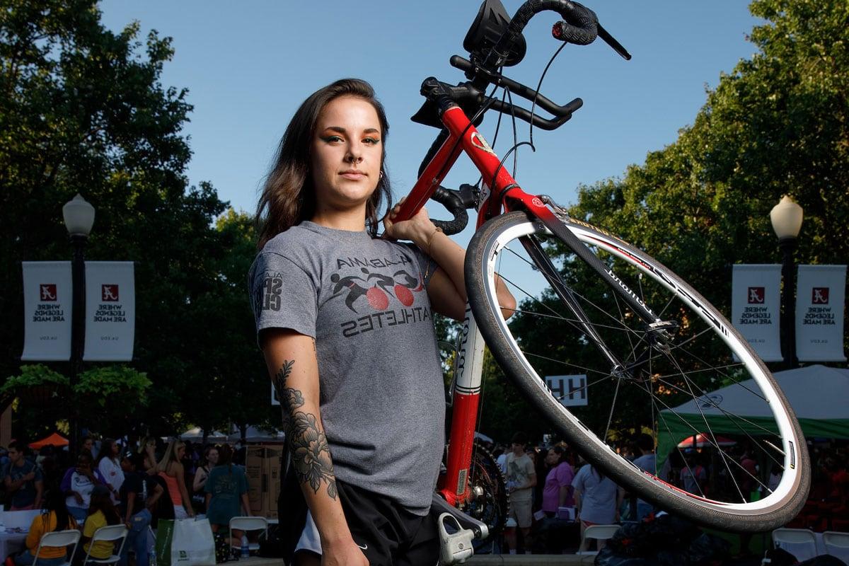 一位代表动感单车俱乐部的学生拿着她的自行车